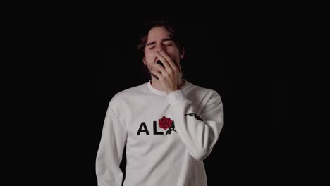 trendy young man yawning extremely, tired gesture, wide, black background