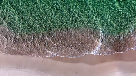 una playa pacífica con olas rompiendo en la arena y una ola verde del océano que viene de la orilla y una ola verde del océano que viene de la parte superior