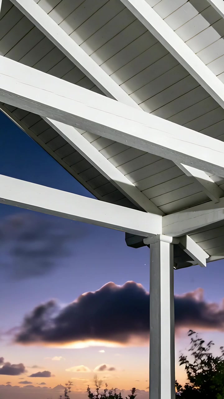 Vertikales Video: Sinkende Sonne beleuchtet weiße Pergola-Sparren und Querbalken auf der Terrasse, Wolken ziehen vorbei.