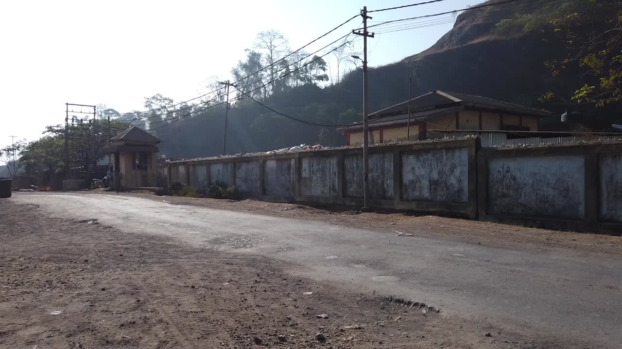 재활용을 위해 수거된 쓰레기와 함께 지나가는 사람들과 트럭이 있는 외부 벽에서 포트 블레어 시의회 폐기물 재활용 공장