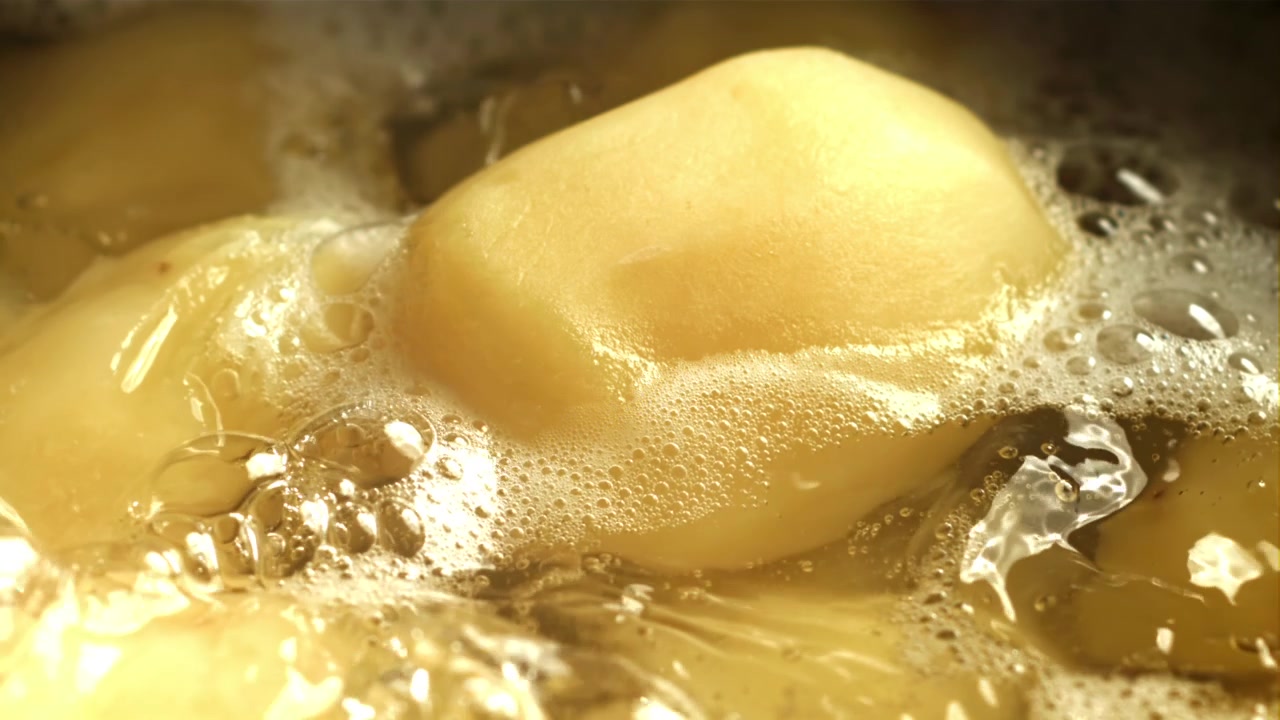 泡が立った熱湯で茹でられる皮をむいたジャガイモ