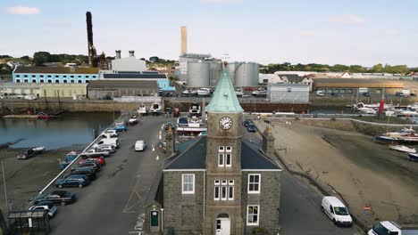 Vuelo-Circular-De-Drones-Centrado-En-La-Torre-Del-Reloj-St-Sampsons-Harbour-Guernsey-Que-Muestra-El-Puerto-Deportivo,-El-Astillero,-La-Central-Eléctrica,-Los-Muelles,-El-Muelle-Y-La-Urbanización-Circundante