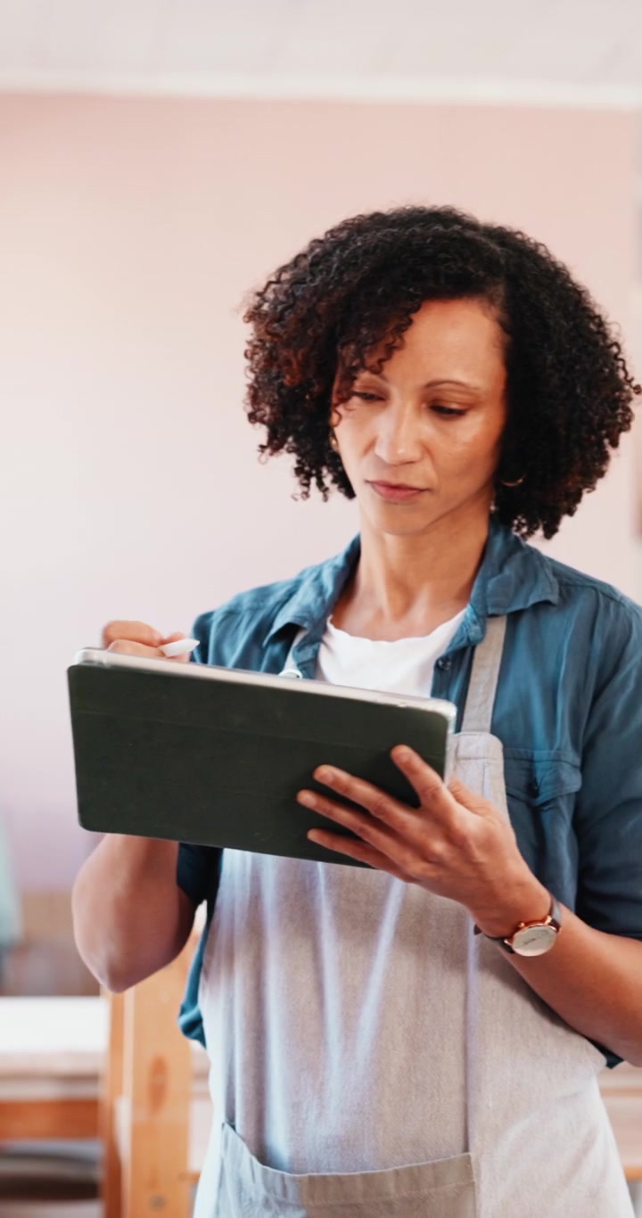 Woman in Apron Using Tablet and Stylus in Studio