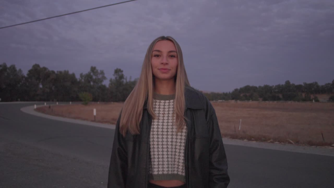 Smiling Young Woman in Leather Jacket at Sunset