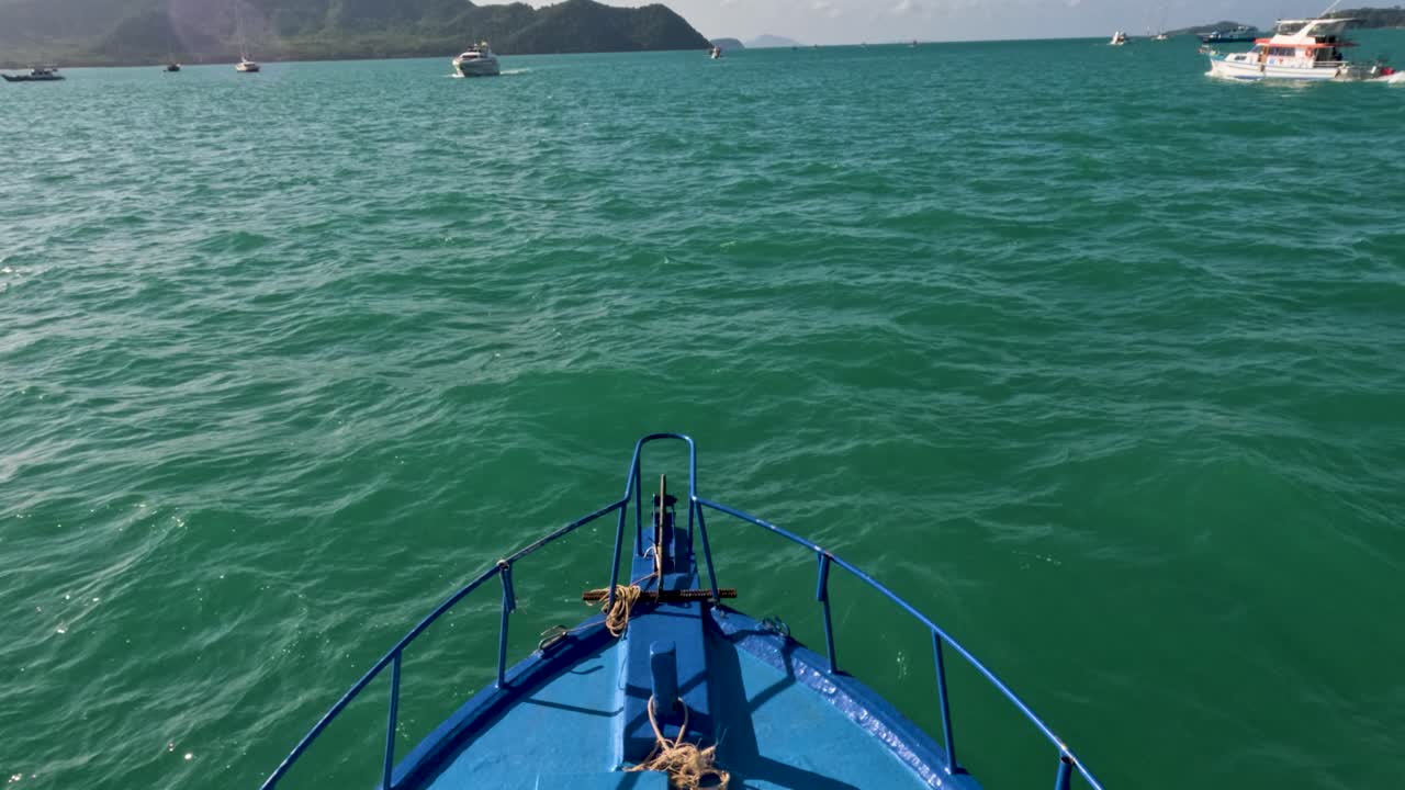 A vibrant blue boat navigates through Phuket's emerald waters under clear skies, capturing a serene maritime adventure
