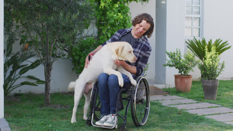 smiling caucasian disabled man in wheelchair playing with pet dog in street