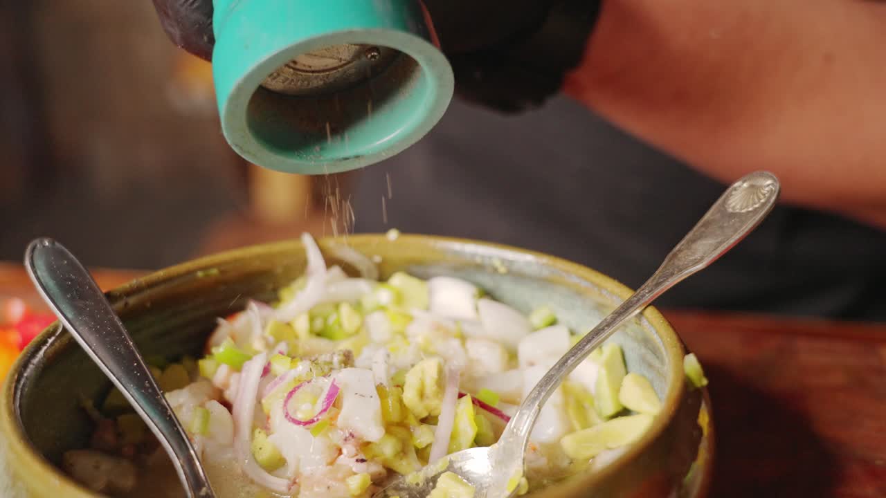 preparación de ceviche - toma en cámara lenta que captura al chef condimentando y aromatizando el famoso plato peruano con molinillo de pimienta, concepto de escena culinaria