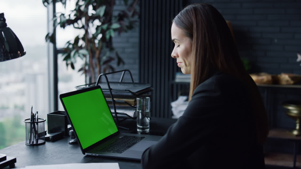 mujer de negocios llamando video en una computadora portátil con pantalla verde en la oficina