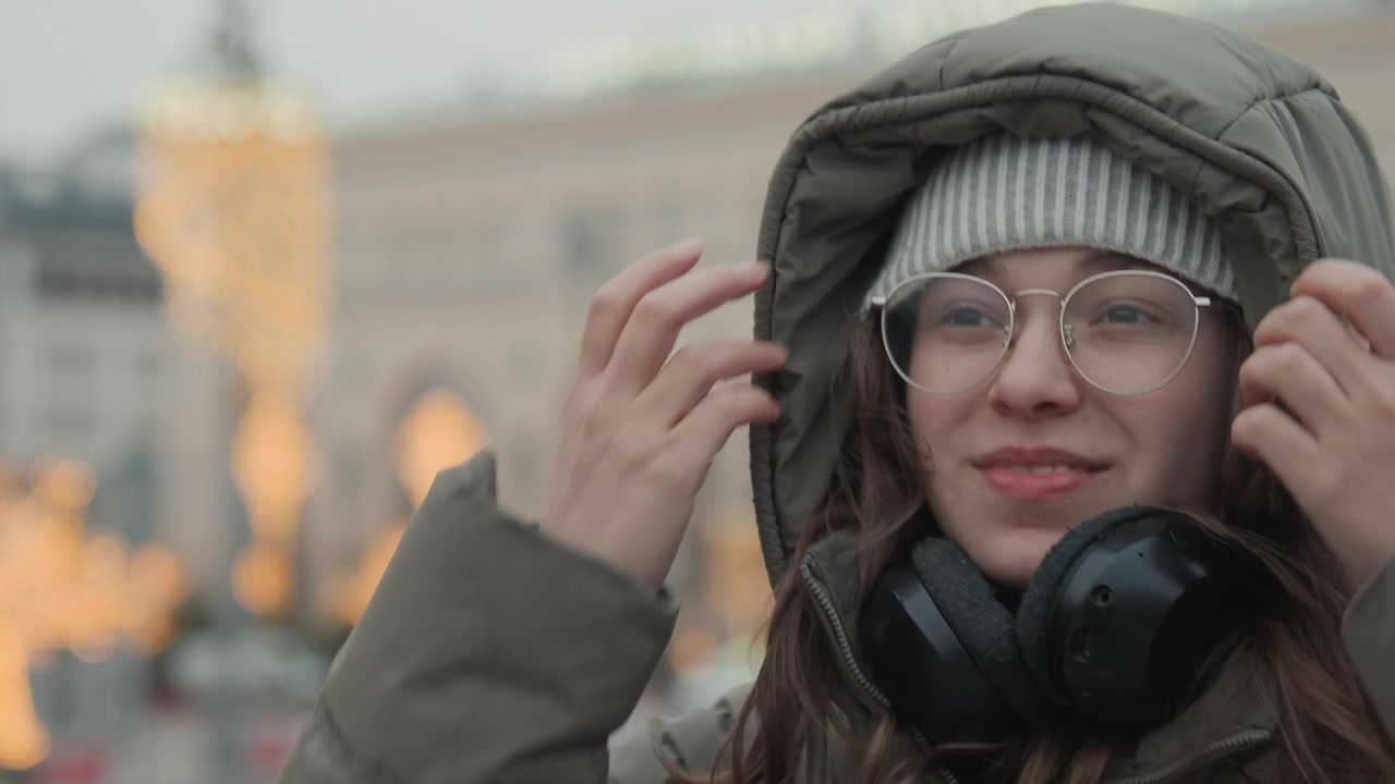 Mulher feliz com roupas de inverno elegantes. Senhora alegre desfrutando das luzes da cidade e da atmosfera festiva. Mulher urbana com vestuário de inverno estiloso, deleitando-se com a cena vibrante da cidade e as celebrações