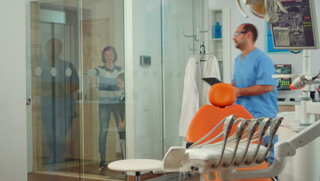 Man-nurse-inviting-kid-patient-in-consultation-dental-room