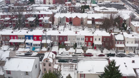 Aerial-of-snow-falling-on-colorful-rowhomes-in-winter