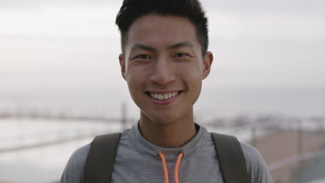 close up portrait of charming young asian man smiling cheerful optimistic by cloudy seaside