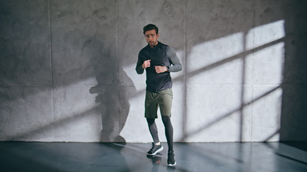 Tired athlete training boxing punching air in loft gym. Man cardio exercising