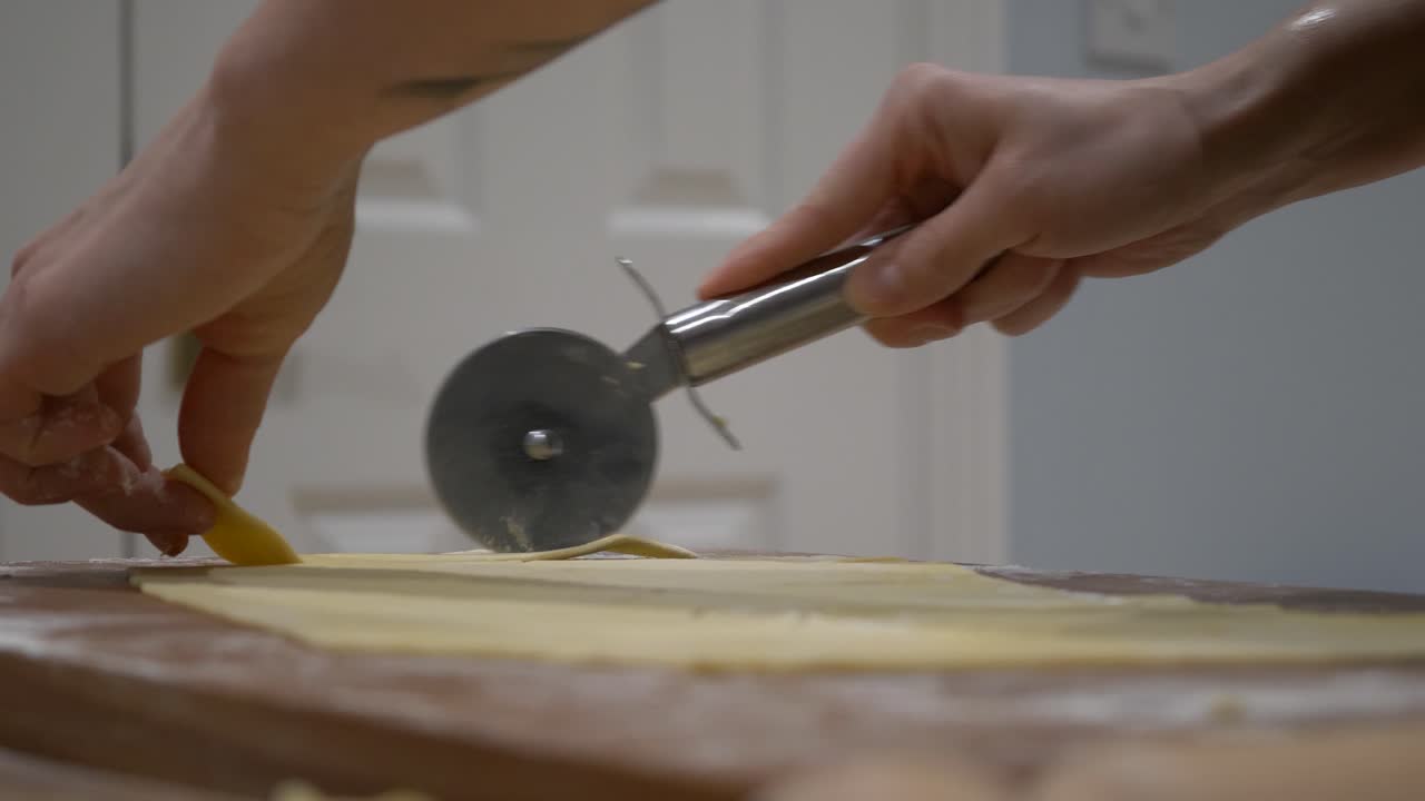 Utilizzo di una rotella taglia pizza per affettare rotoli di pasta per il piatto polacco Faworki