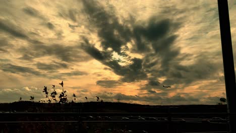 El-Avión-Se-Acerca-Para-Aterrizar-Al-Atardecer,-Vuela-Bajo-Sobre-La-Carretera,-Muchas-Nubes-En-El-Cielo