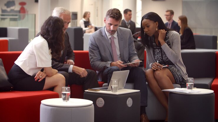 Businesspeople Meeting In Busy Lobby Of Modern Office