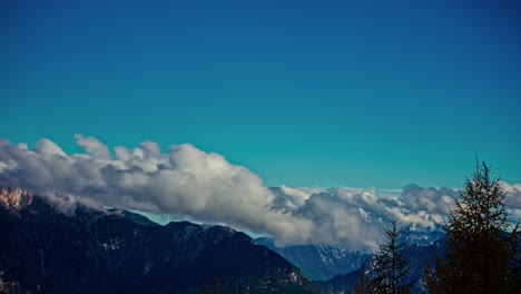 Strong-white-clouds-roll-as-they-are-blown-across-rocky-mountain-peaks-in-sky