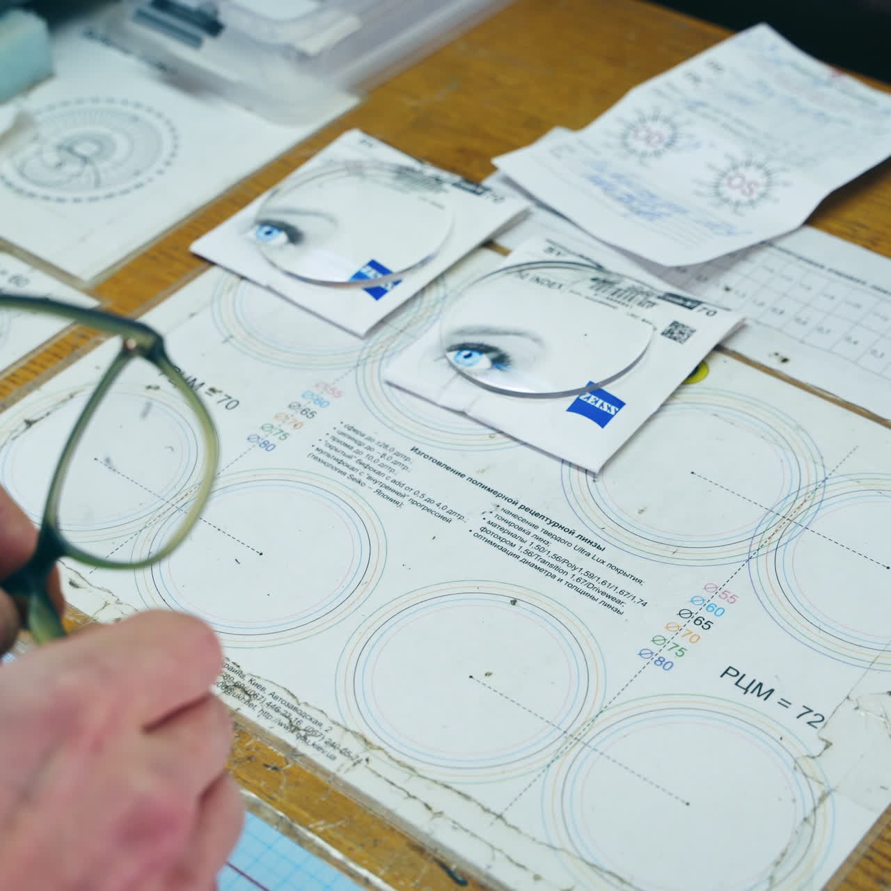 Technician works with glasses in the laboratory. Hands of a man taking off glass from old eyeglasses on the table.