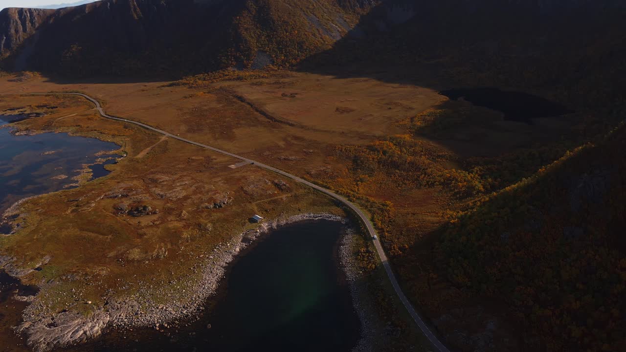 Road stretching through autumn plains and lakes, dramatic hills in Vestarelen