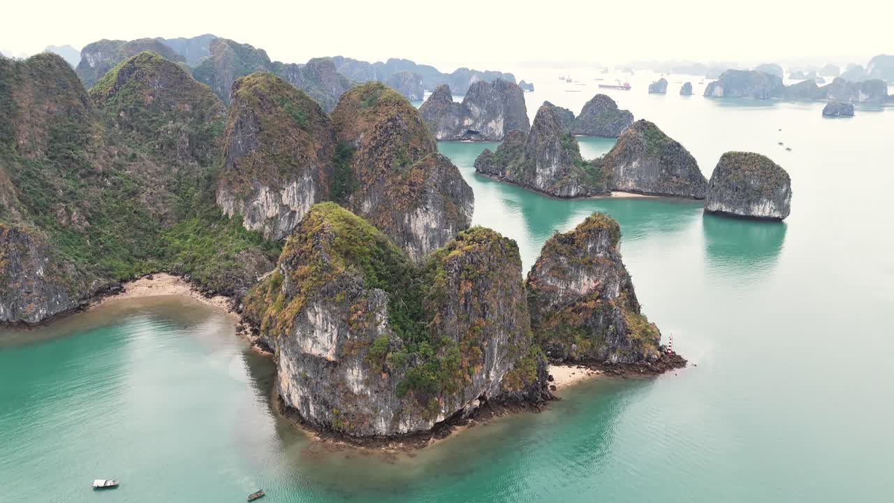 Turquoise waters surround towering limestone islands in Ha Long Bay, Vietnam, with scattered beaches creating a serene coastal seascape view, orbiting