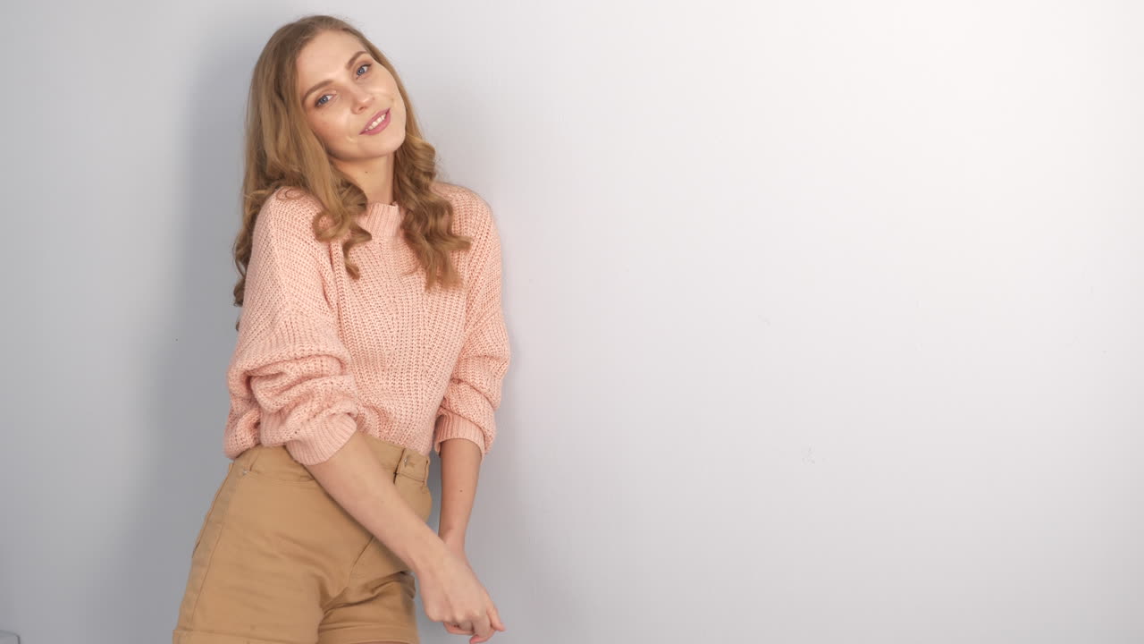 mujer con un suéter rosa y pantalones cortos beige