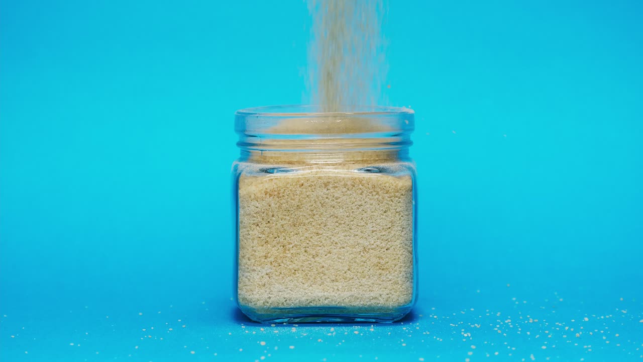 Açúcar Granulado Despejando em um Pote de Vidro Transparente