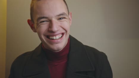 flattered young man smiling wide touching his head and face while staring at the camera - closeup shot