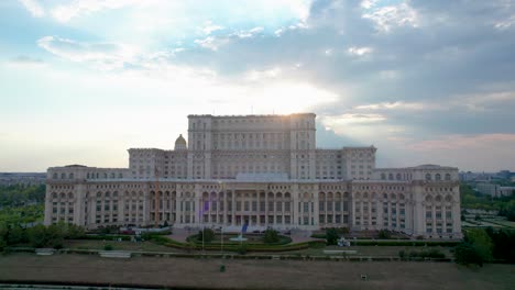 Stunning-Rotating-Drone-View-of-the-Palace-of-Parliament-in-Bucharest,-Romania-at-Sunset-with-Sun-Rays-Bursting-Over-the-Building