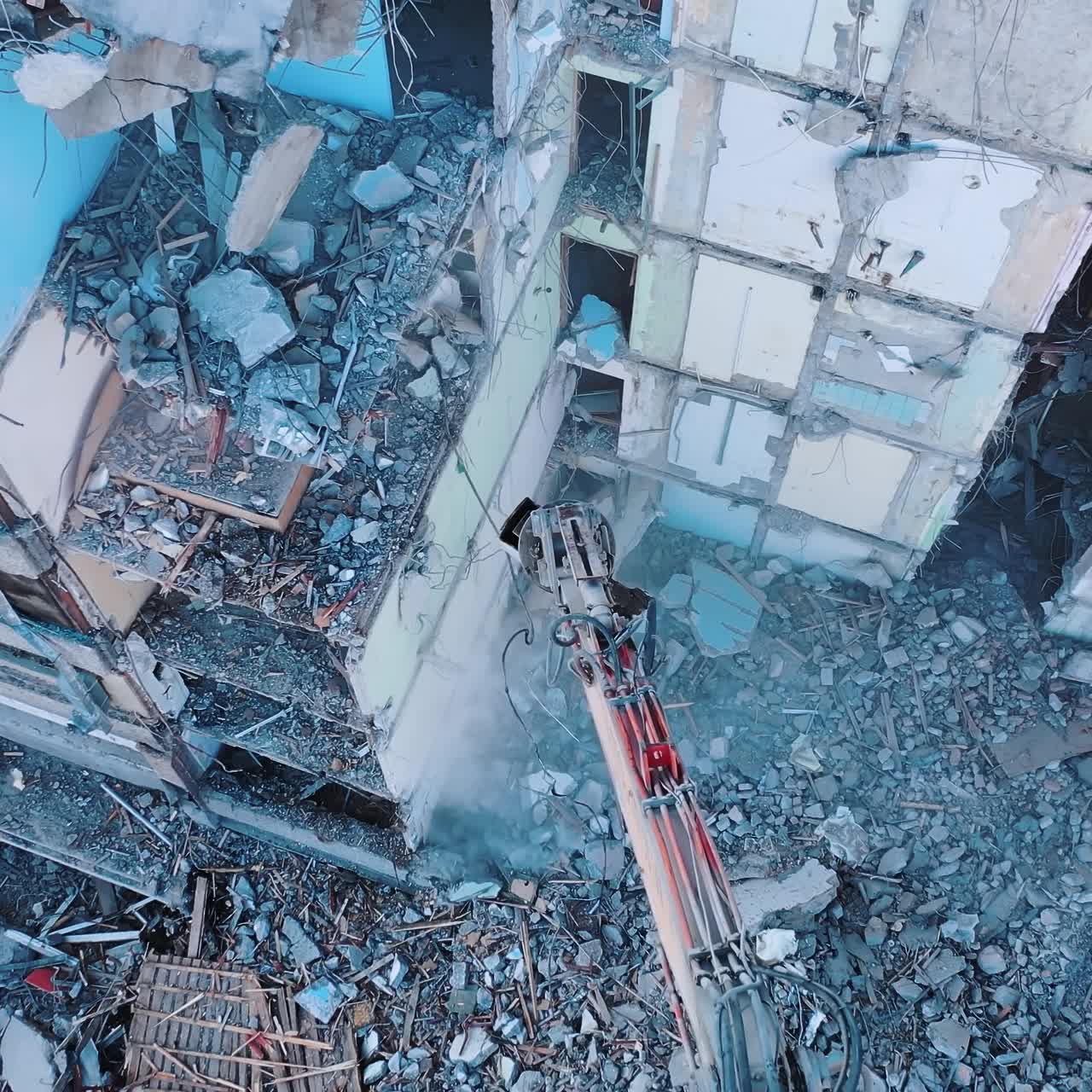 Heavy machinery dismantling the old building. Excavator disassembling the ruins of the construction. View from above