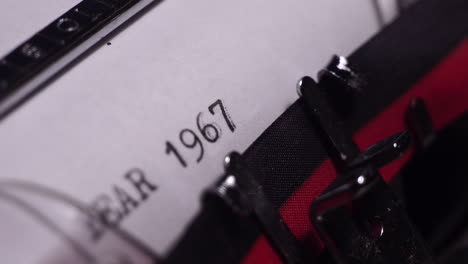 year 1967, typing in vintage typewriter on white paper, close up