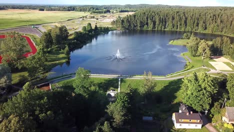 Fliegende-Drohnenaufnahme-Des-Erholungskomplexes-Neben-Dem-See-Mit-Springbrunnen---Aufsteigende-Luftaufnahme