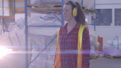 animation of light spots over caucasian female worker with safety headphones in warehouse