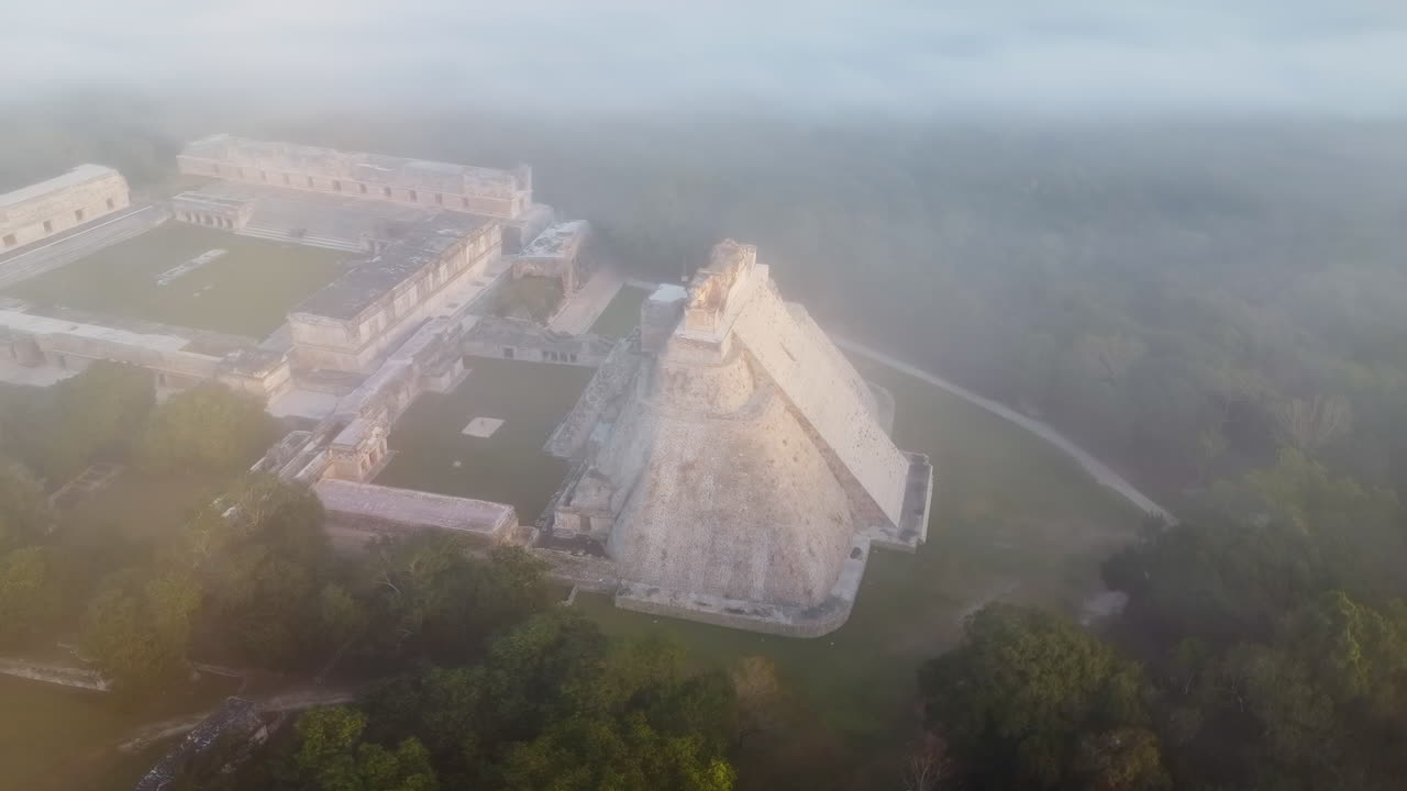 Vista aerea con drone del Tempio delle Iscrizioni nel sito archeologico di Palenque che emerge attraverso la nebbia mattutina nella giungla del Chiapas, Messico, mostrando antiche rovine Maya circondate da una densa foresta pluviale.
