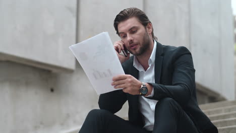 Business-man-calling-on-mobile-phone-in-city.-Executive-looking-at-documents