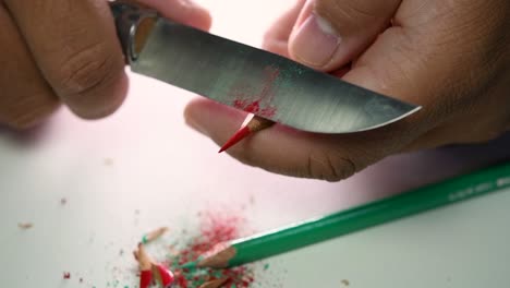 Footage-of-hands-slowly-sharpening-a-pencil-and-some-coloured-pencils-with-a-sharp-knife