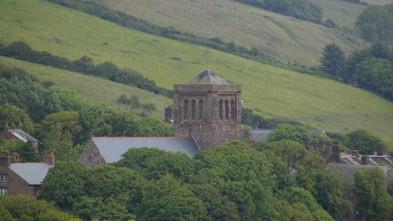 long shot of st bees Priory church with trees and hills. West lake district