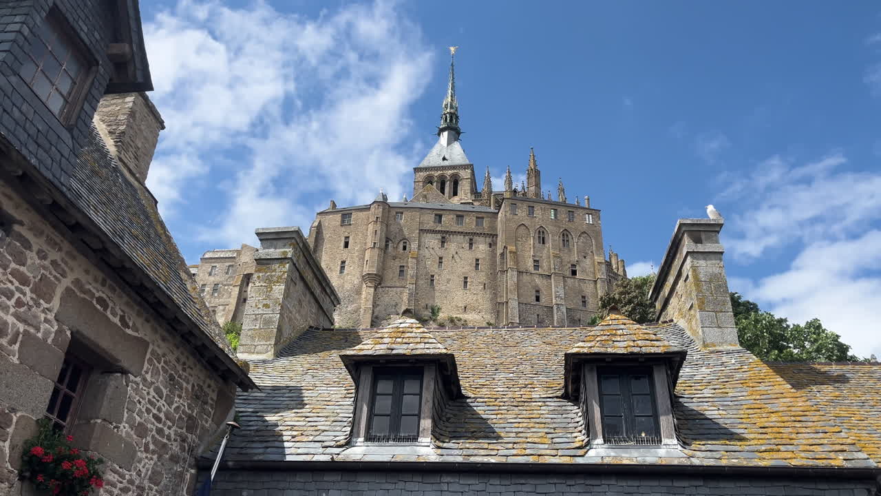 Mont Saint-Michel castle towering over rooftops under a sunny sky in France