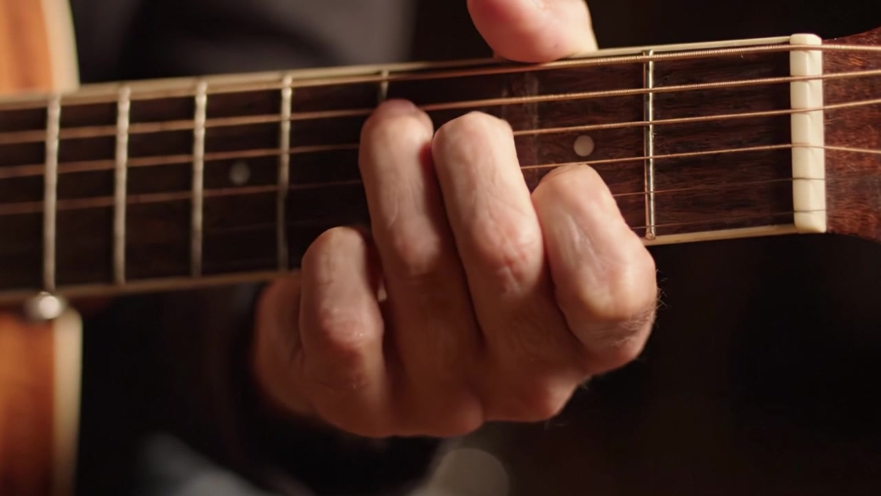 Catturare l'Essenza del Suonare la Chitarra: Un Primo Piano sul Posizionamento delle Mani e sulla Tecnica Coinvolti nello Strimpellare e nell'Esecuzione di Accordi su una Chitarra Acustica