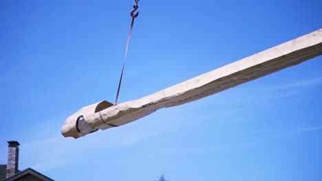 large wooden beam being lifted by crane