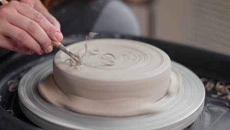 process of shaping clay piece with a tool in a pottery studio. close-up, slow motion