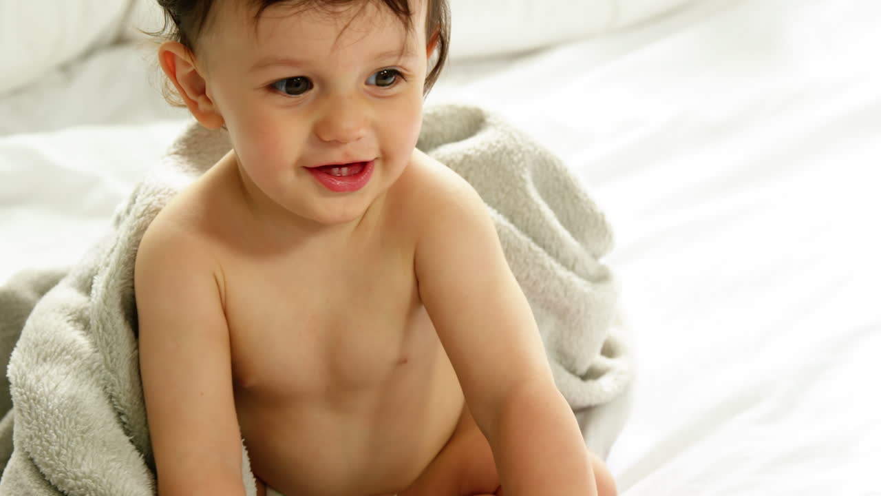 retrato de un bebé sonriente sentado en una cama
