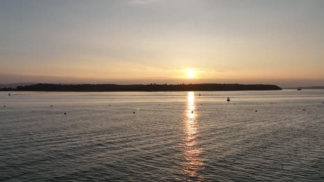 Bournemouth,-Großbritannien---Fliegen-Knapp-über-Der-Ozeanoberfläche-Und-über-Eine-Wunderschöne-Insel,-Die-Von-Der-Untergehenden-Sonne-Beleuchtet-Wird