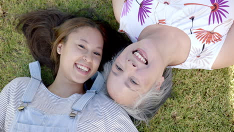 lying on grass, asian grandmother and granddaughter smiling and enjoying time together