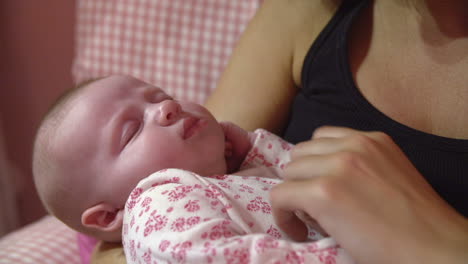 mother at home cuddling sleeping newborn baby in nursery