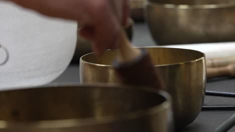 a hand delicately taps the singing bowl, initiating its use in sound bathing therapy in the sacred valley of the cuzco region, peru - close up