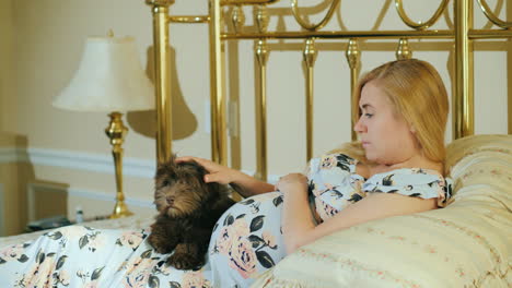 a puppy lies on the belly of a pregnant woman who is stroking him