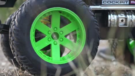 Close-up-shot-on-parts-of-RC-monster-truck-toy,-moving-on-soil-ground-120fps