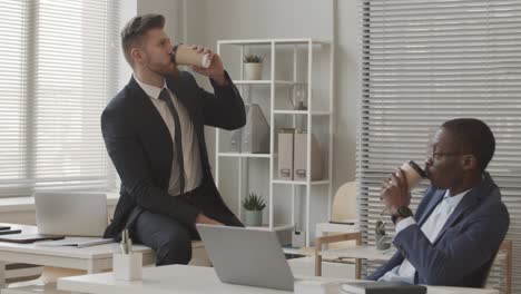 male brokers chatting during coffee break in office