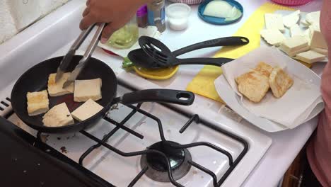 un cocinero friendo lonchas de queso en una sartén