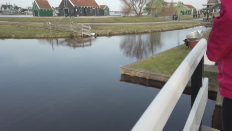 Walking-at-the-bridge-over-a-calm-small-river-in-the-historical-windmill-Zaanse-Schans-in-Holland